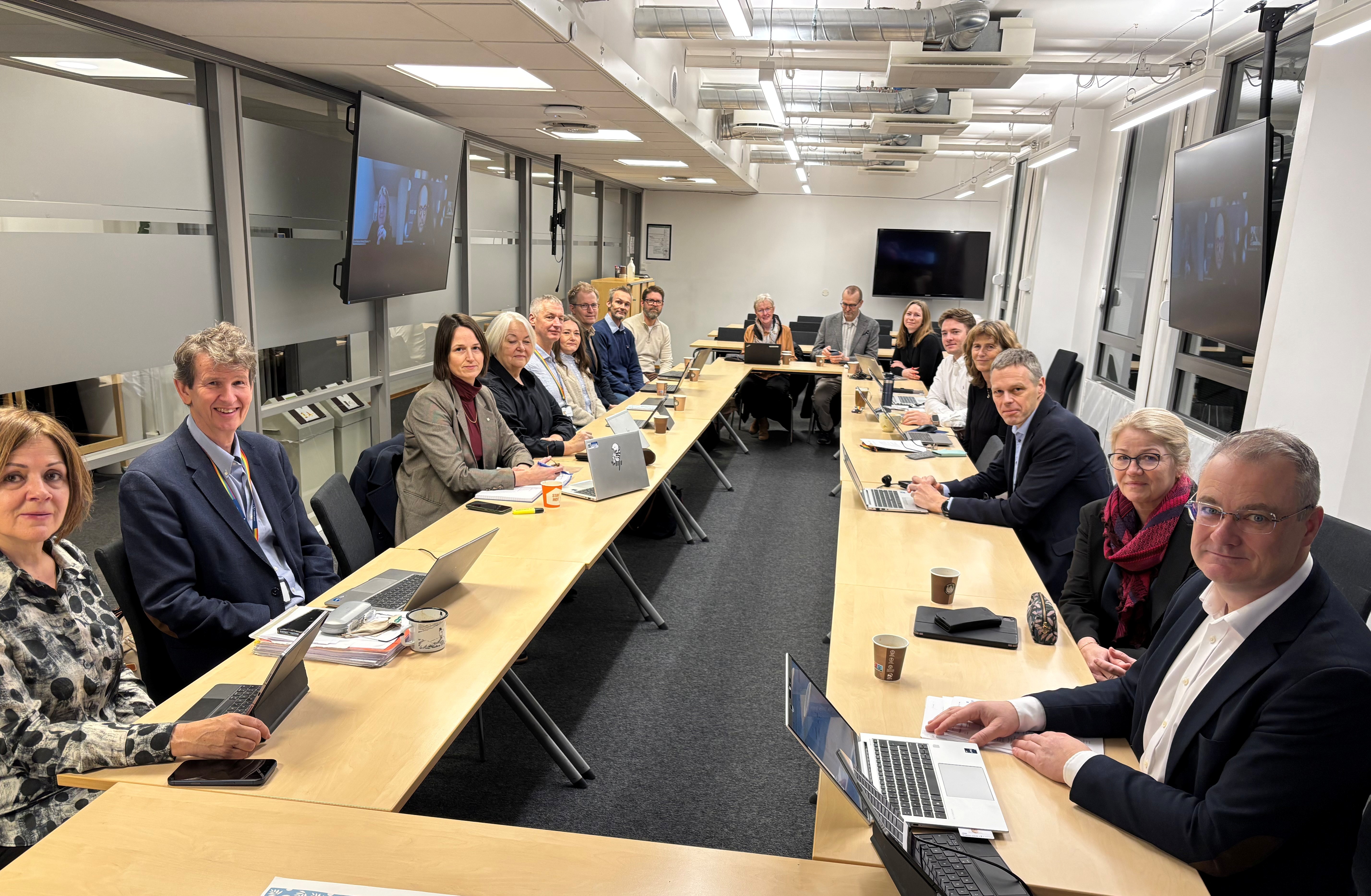 En gruppe mennesker som sitter ved lange bord med bærbare datamaskiner