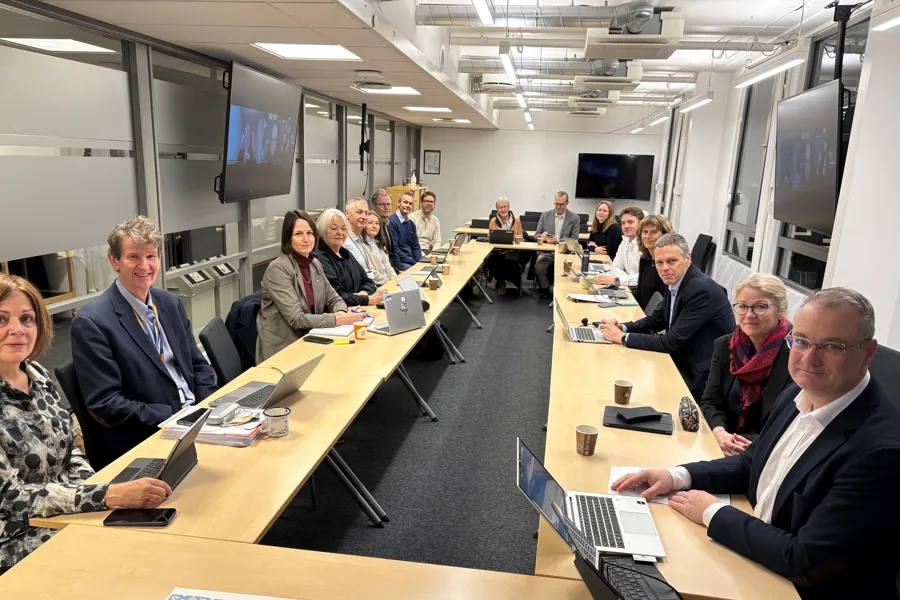 En gruppe mennesker som sitter ved lange bord med bærbare datamaskiner